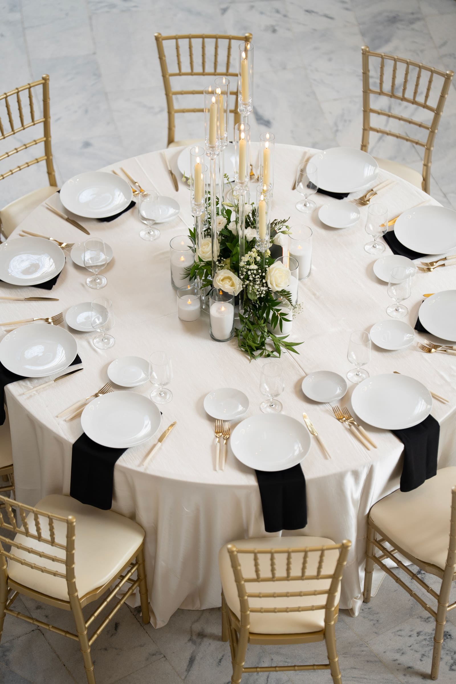 A reception table set with gold chairs and white florals